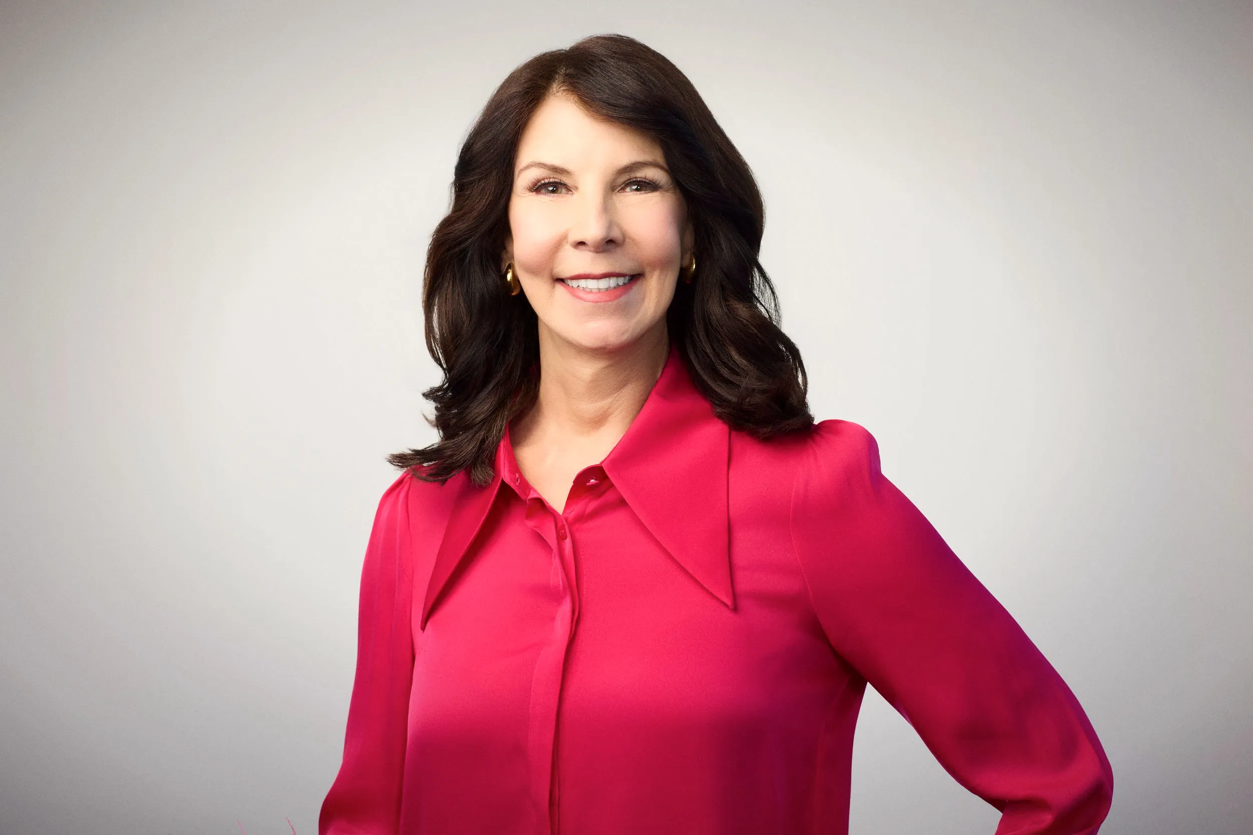 Giulia Kennedy, smiling, in a bright pink blouse against a light background