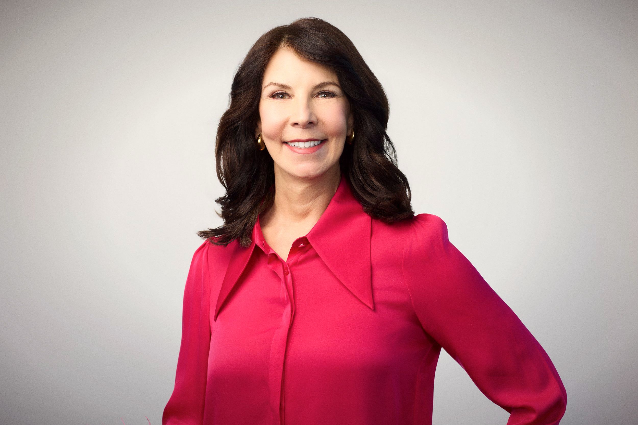Giulia Kennedy, smiling, in a bright pink blouse against a light background